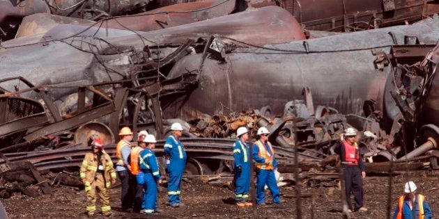 File- In this July 6, 2013 file photo, workers stand before mangled tanker cars at the crash site of the train derailment and fire in Lac-Megantic, Quebec, Canada. On the tranquil bank of the Columbia River in Vancouver, Wash., just across from Portland, Ore., regulators are weighing the fate of what could become the Pacific Northwestâs largest crude oil train terminal: it would receive daily shipments of up to 360,000 barrels of oil via four trains a day rolling through iconic river communities and into the crowded Portland/Vancouver metro area, each train 120 cars and more than a mile long. (AP Photo/Ryan Remiorz, Pool, File)