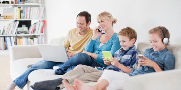 Family enjoying electronics on sofa together
