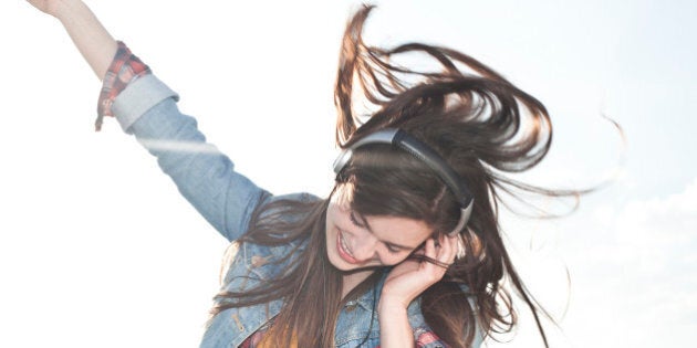 Portrait of happy young woman listening music with headphones