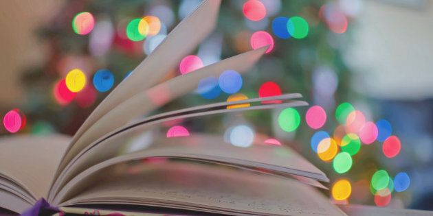 A journal book with colorful holiday christmas lights behind it. The book is open and pages of the book have writing on them