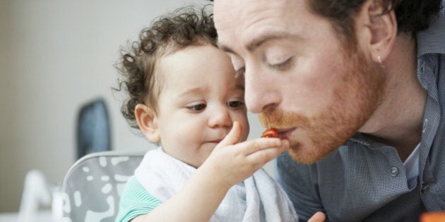 young child feeding father