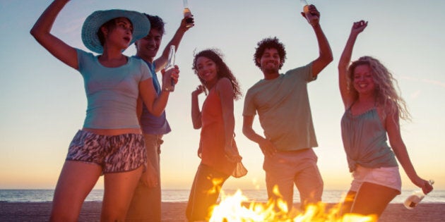 Group of friends making party on the beach with fire and music