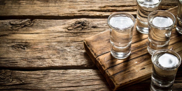 Glasses with vodka on the old Board. On wooden background.