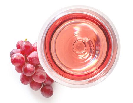 66842048 - glass of rose wine and grapes isolated on white background from top view