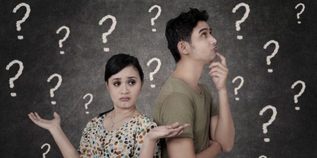 Confused couple with question marks on blackboard