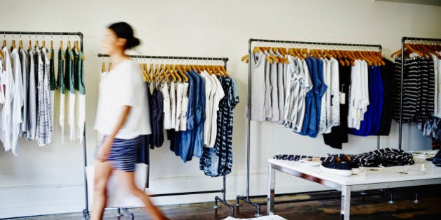 Female customer with shopping bag walking in clothing boutique