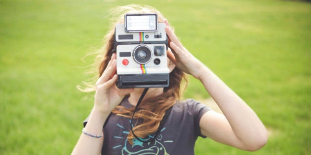 Caucasian girl taking instant photograph outdoors