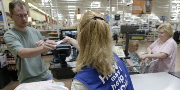 UNITED STATES - AUGUST 15: Louann Cavinder, a cashier at the Wal-Mart store in Grove City, Ohio hands a sales receipt to a customer at her register Tuesday, August 15, 2006. Wal-Mart Stores Inc., the world's biggest retailer, reported the first decline in profit in more than a decade after selling its German chain. Sales increased less than analysts estimated. (Photo by Jay Laprete/Bloomberg via Getty Images)