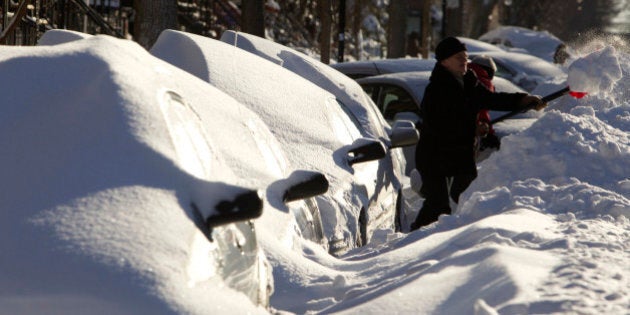 A woman shovels snow next to cars buried under snow in Montreal, December 28, 2012. REUTERS/Olivier Jean (CANADA - Tags: ENVIRONMENT SOCIETY)