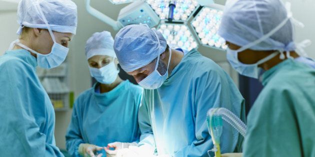 Group of surgeons performing surgery on patient in operating room