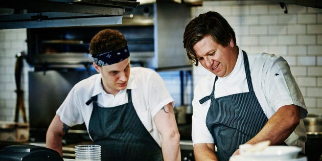 Executive chef demonstrating how to process duck to sous chef in restaurant kitchen