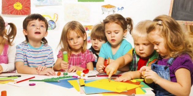 Group of little kids painting with pencils and gluing with glue stick on art class in kindergarten