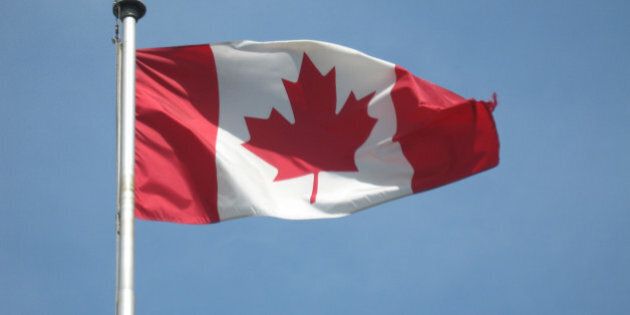 A Canadian flag blowing in the wind on a perfect day.