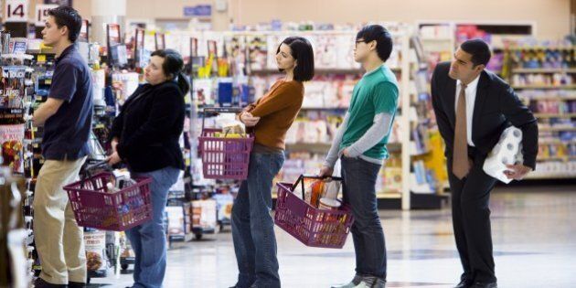 People waiting in line with shopping baskets at grocery store