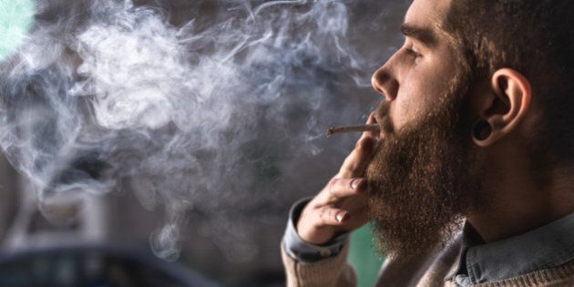 Close up of hipster man smoking weed cigarette.