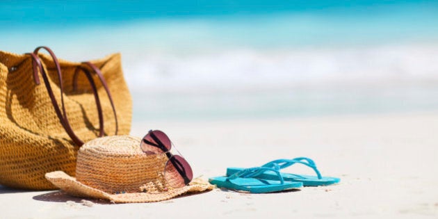 Straw hat, bag, sun glasses and flip flops on a tropical
