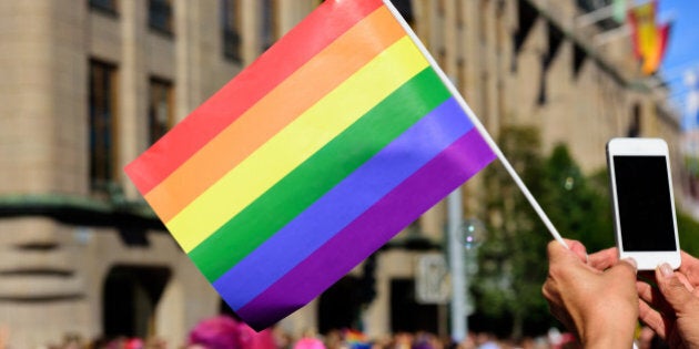 Pride flag and spectator taking pictures with mobile phone