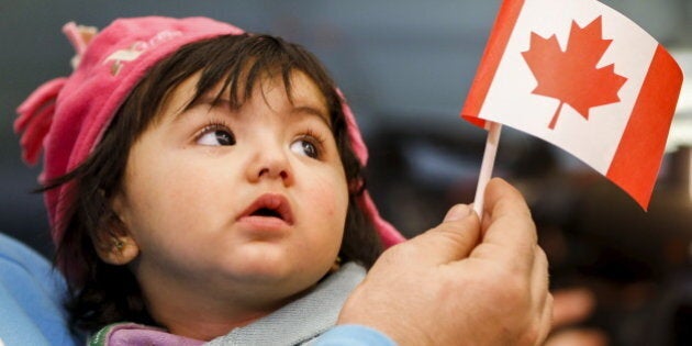 A young Syrian refugee looks up as her father holds her and a Canadian flag at the as they arrive at Pearson Toronto International Airport in Mississauga, Ontario, December 18, 2015. REUTERS/Mark Blinch TPX IMAGES OF THE DAY