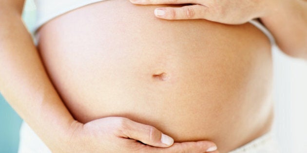 Mid section of a woman holding her pregnant belly