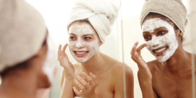 Diverse friends smiling while applying skincare face masks to their faces