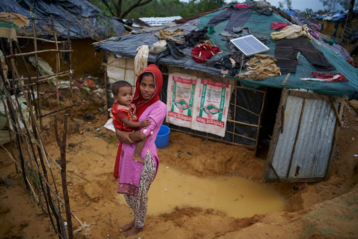 Zohra tient sa soeur âgée de deux ans, devant leur abri improvisé au camp de fortune Kutupalong pour personnes réfugiées rohingyas, au Bangladesh.