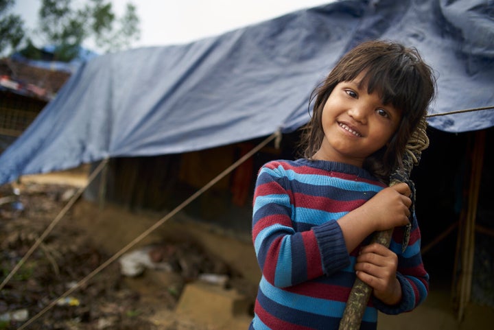 Une jeune fille rohingya sourit devant l'abri de fortune de sa famille au camp de fortune Balukhali pour personnes réfugiées rohingyas, au Bangladesh.