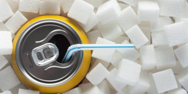 Unhealthy food concept - sugar in carbonated drink. Sugar cubes as background and canned drink