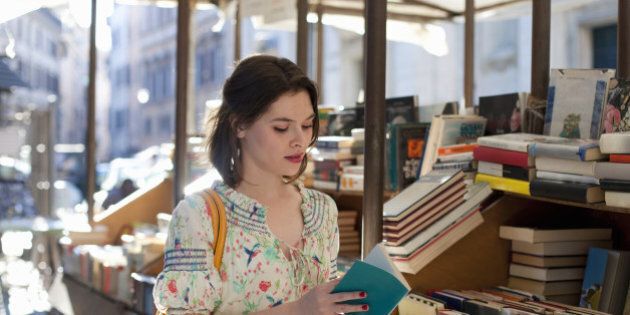 young woman flipping through book at bookstall