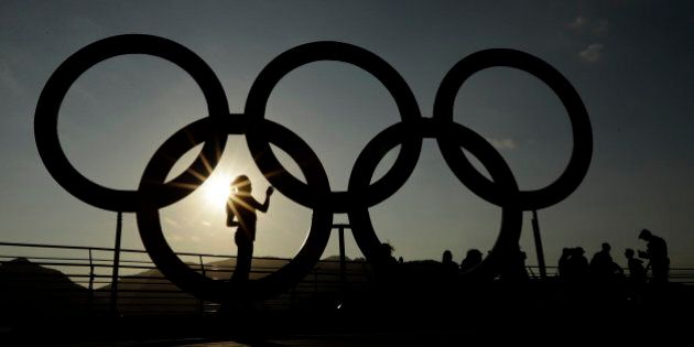 A woman is silhouetted by the setting sun as she looks at a set of Olympic rings in the Olympic Park ahead of Rio's 2016 Summer Olympics, in Rio de Janeiro, Brazil, Thursday, Aug. 4, 2016. (AP Photo/Charlie Riedel)