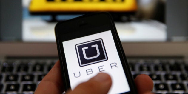 An illustration picture shows the logo of car-sharing service app Uber on a smartphone next to the picture of an official German taxi sign September 15, 2014. REUTERS/Kai Pfaffenbach/Illustration/File Photo