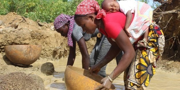 Daby dort sur le dos de sa mère pendant que celle-ci drague la rivière à la recherche d’or dans l’ouest du Mali.