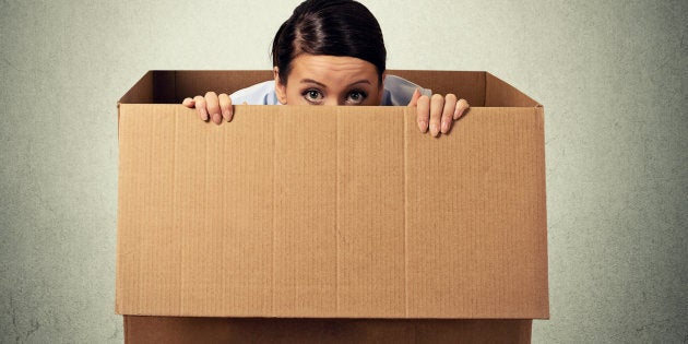 Young woman hiding in a carton box