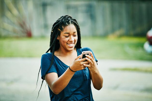 Laughing young woman looking at smartphone on summer evening