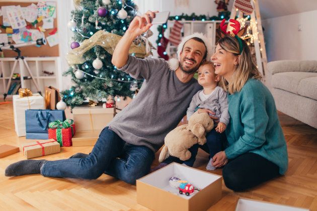 Photo of a cheerful young family, posing for a selfie during Christmas holiday celebration