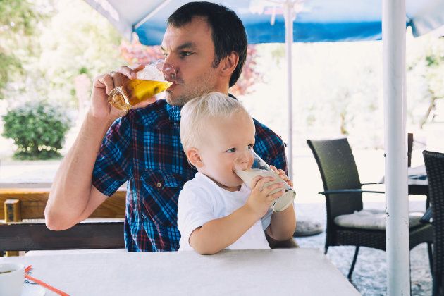 Father drinks beer, child drinks juice in a beach bar. Dad and son are best friends! Family spend time together in a cafe, restaurant in a summer day. Lifestyles, Family, Vacation concept.