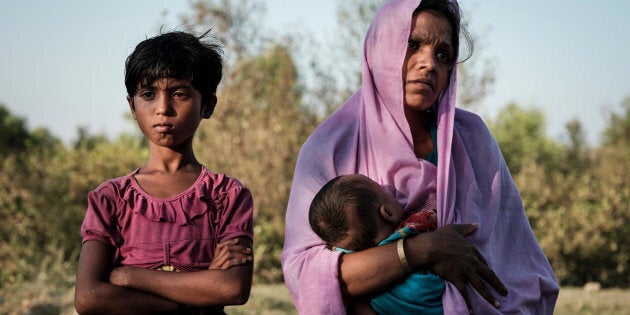 Mariom Khatun, réfugiée rohingya âgée de 25 ans, tient dans ses bras son bébé, Firuz Ahmed, âgé de 5 mois, alors qu’ils se reposent sur les rives de la rivière Naf, dans le district de Cox’s Bazar, au Bangladesh, après un périple de six heures pour traverser la rivière sur une embarcation de fortune.