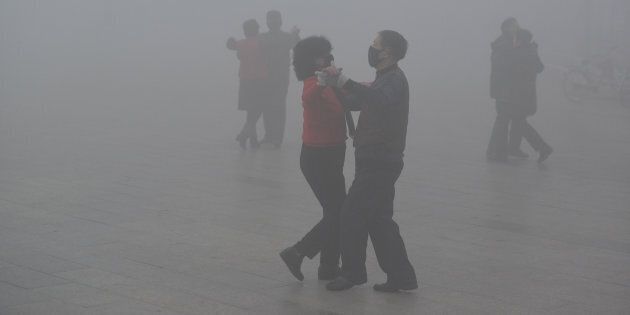 Des danseurs portent un masque dans un smog épais à Fuyang, en Chine.