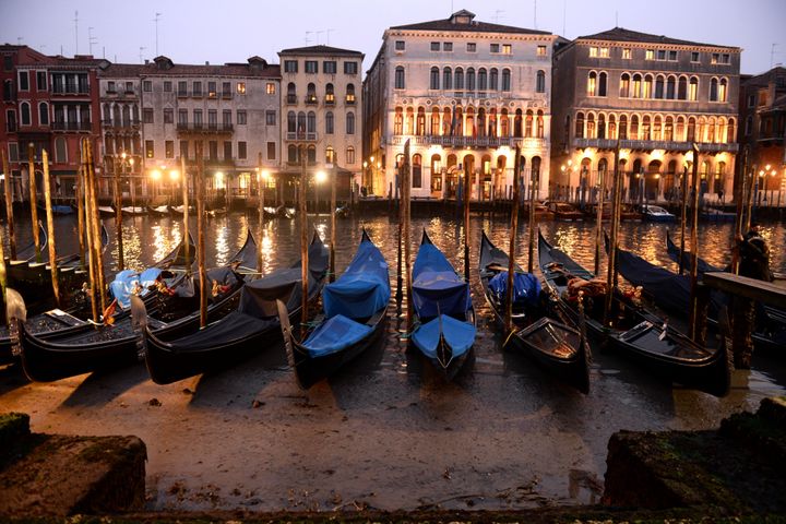 Gondolas are seen tied up in Venice Canal Grande, near Rialto bridge, on January 31, 2018, as exceptionally low tides have drained the lagoon city. The unusually low tides caused a record low water measuring around 70 cm which caused problems to the water traffic in the historic center of Venice. / AFP PHOTO / MARCO SABADIN