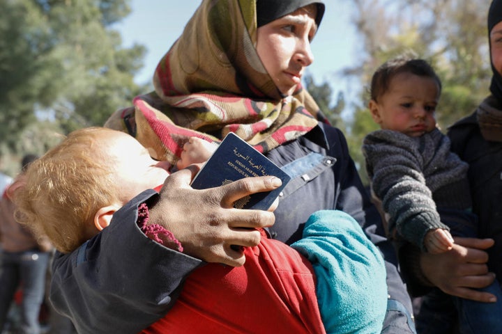 Le 20 mars 2018, dans la Ghouta orientale, en Syrie, une femme transporte un enfant au complexe électrique qui abrite aujourd'hui près de 13 000 personnes ayant fui la Ghouta orientale assiégée.