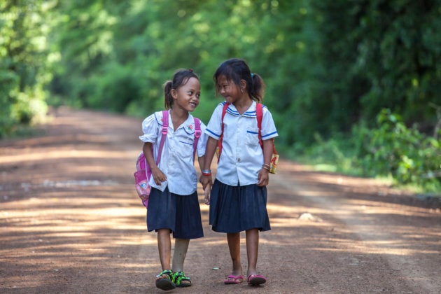 Channa (7 ans), amputée, marche avec une camarade de classe sur le chemin de l'école au Cambodge