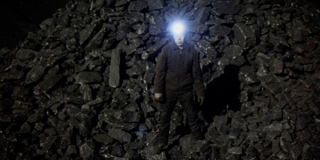 SHANXI, CHINA -NOVEMBER 25: (CHINA, HONG KONG, MACAU, TAIWAN OUT) A Chinese mine worker wears a headlamp as he stands in a pile of coal at a mine on November 25, 2015 in Shanxi, China. A history of heavy dependence on burning coal for energy has made China the source of nearly a third of the world's total carbon dioxide (CO2) emissions, the toxic pollutants widely cited by scientists and environmentalists as the primary cause of global warming. China's government has publicly set 2030 as a deadline to reach the country's emissions peak, and data suggest the country's coal consumption is already in decline. (Photo by Kevin Frayer/Getty Images)