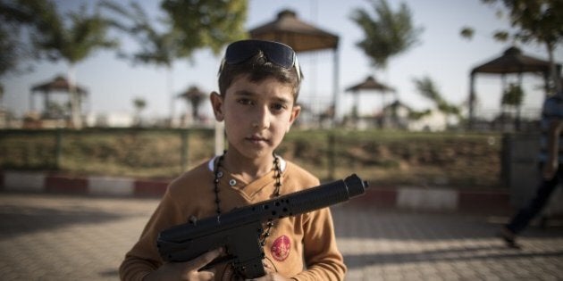 SANLIURFA, TURKEY - SEPTEMBER 24: A Syrian refugee boy poses with a toy gun at a tent city in the Akcakale...
