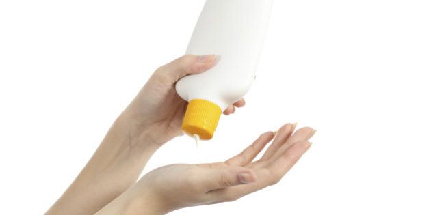 Hands applying sunscreen protection from a bottle isolated on white background