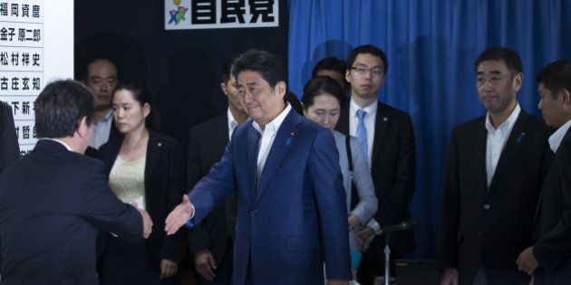 Shinzo Abe, Japan's prime minister and president of the Liberal Democratic Party (LDP), center, shakes hands with a party executive as he arrives at a conference room in the party's headquarters after the upper house election in Tokyo, Japan, on Sunday, July 10, 2016. Abe's conservative ruling coalition and its allies are set for a big win in Sunday's upper house election, an NHK exit poll showed, and may achieve the two-thirds majority that would allow him to press ahead with plans to revise the pacifist constitution. Photographer: Tomohiro Ohsumi/Bloomberg via Getty Images
