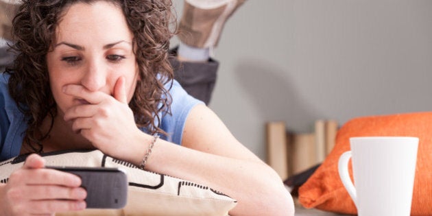 mumbling expression of a lying girl reading something on her mobile while lying on the floor on a pillow