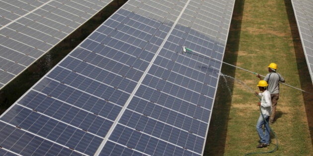 Workers clean photovoltaic panels inside a solar power plant in Gujarat, India, in this July 2, 2015 file photo. The likely collapse of SunEdison Inc's solar project in India, the first of 32 planned