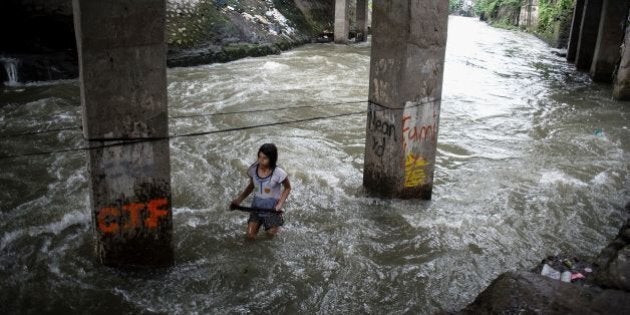 A girl plays at a swollen creek under a bridge in Manila on October 16, 2016.Typhoon Sarika lashed the main Philippine island of Luzon on October 16, flattening homes and toppling trees and power pylons as more than 12,000 people fled to safer ground, officials said. Shanties built beside a river, under a creek are the usual victims of floodings. / AFP / NOEL CELIS (Photo credit should read NOEL CELIS/AFP/Getty Images)