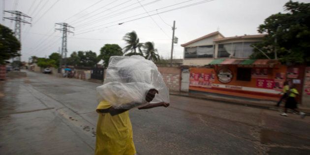 A man crosses a street using a garbage bag as protection from a light rain, in Port-au-Prince, Haiti, Monday, Oct. 3, 2016. Major Hurricane Matthew is slowly churning northward across the Caribbean and meteorologists say the powerful storm is expected to approach Jamaica and southwest Haiti by Monday night. (AP Photo/Dieu Nalio Chery)