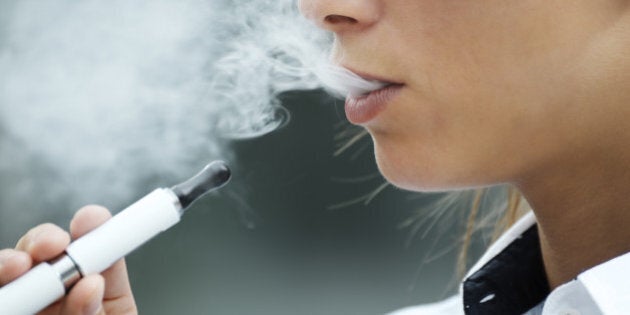 closeup of woman smoking e-cigarette and enjoying smoke. Copy space