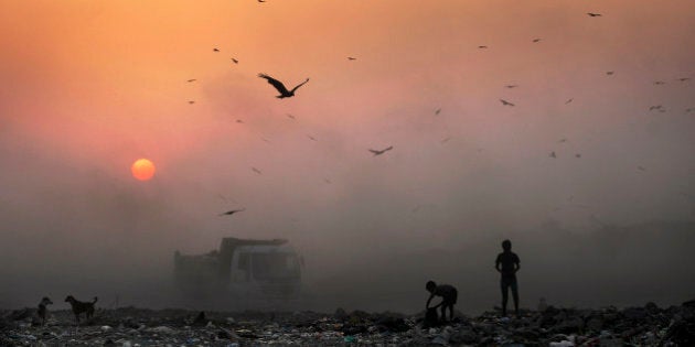 FILE- In this Oct. 17, 2014, file photo, a thick blanket of smoke is seen against the setting sun as young ragpickers search for reusable material at a garbage dump in New Delhi, India. India launched the Air Quality Index Friday to measure air quality across the nation that is home to some of the most polluted cities in the world. A groundbreaking agreement struck Wednesday, Nov. 12, 2014, by the United States and China puts the world's two worst polluters on a faster track to curbing the heat-trapping gases blamed for global warming. (AP Photo/Altaf Qadri, File)